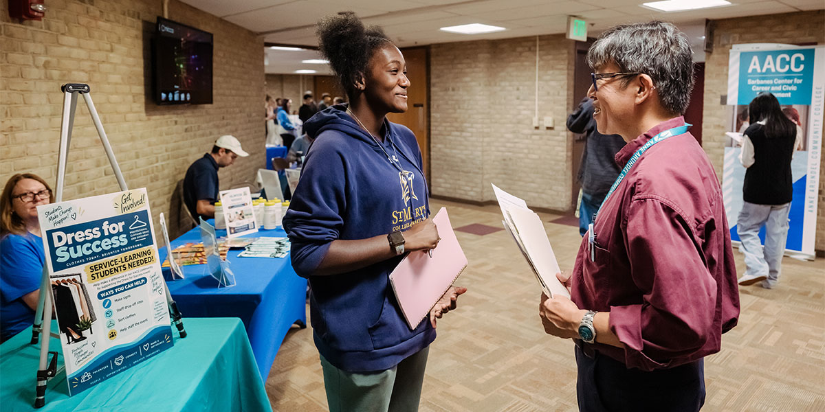 A Sociology professor speaks with a student during a community service fair