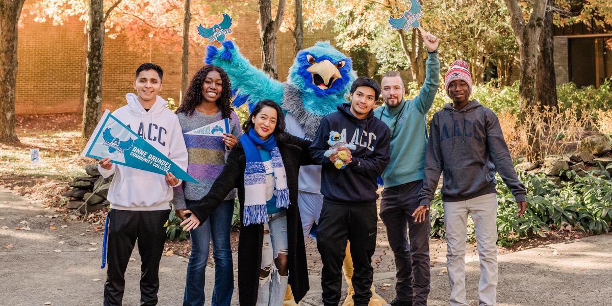 Students laughing and posing with AACC mascot, Swoop.