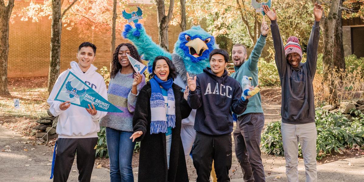 Students laughing and posing with AACC mascot, Swoop.