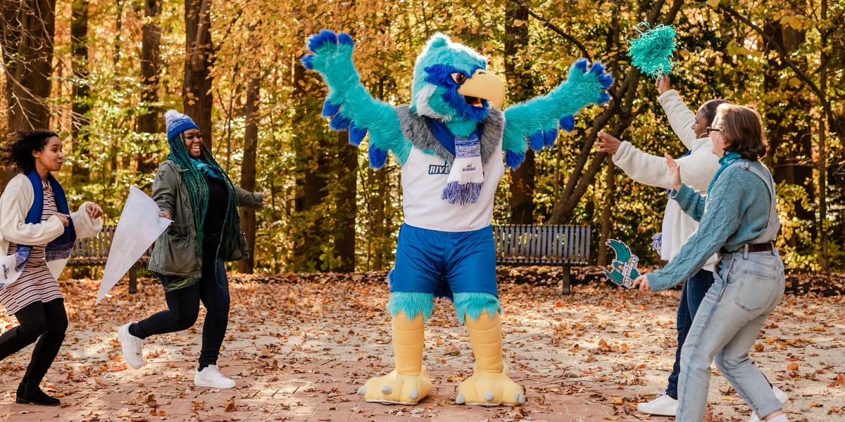 A group of students looking at AACC mascot, Swoop.